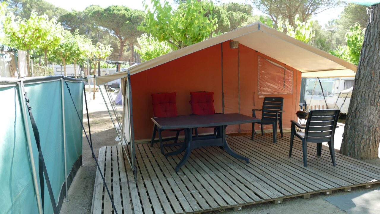 Komfortables Glamping-Zelt mit Holzterrasse, Tisch und Stühlen